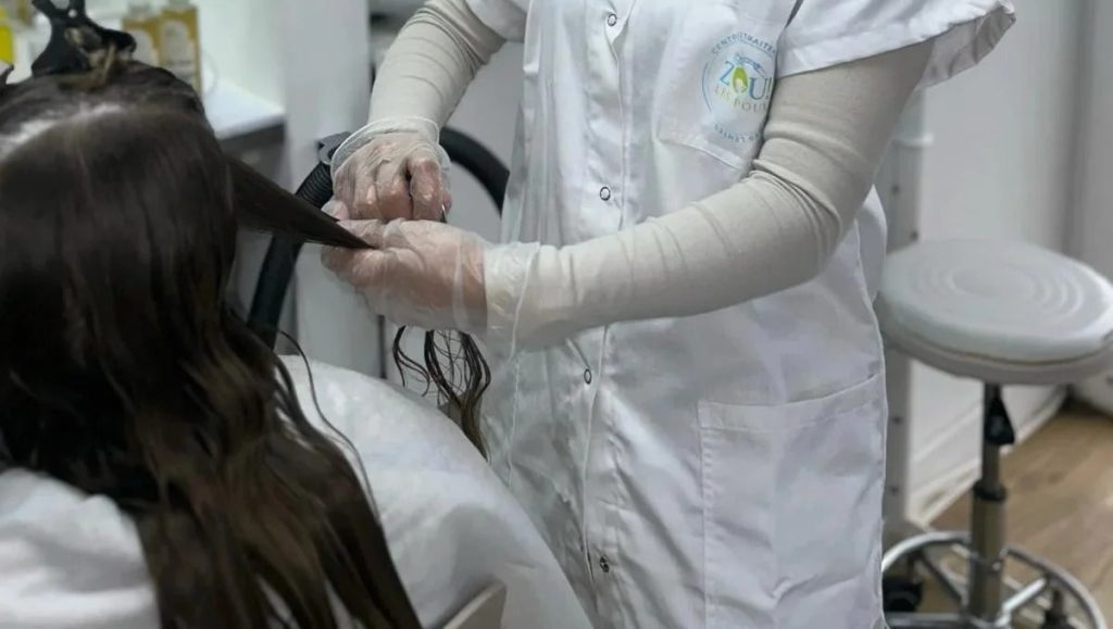 Une professionnelle de la Clinique du Pou manipule les cheveux d'une cliente pour un traitement anti-poux.