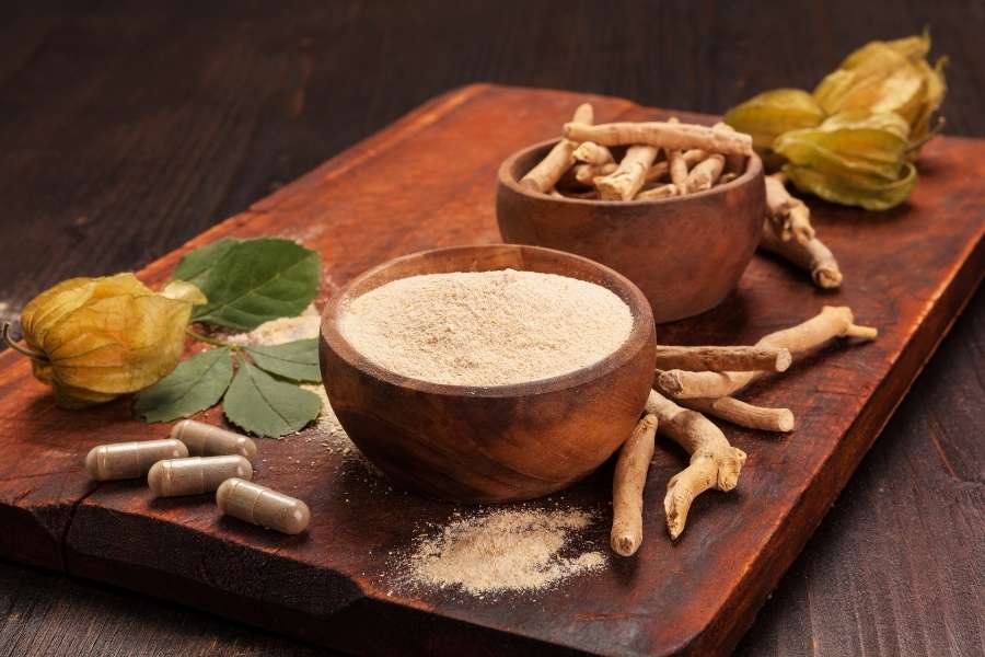Poudre, racines séchées et gélules d'Ashwagandha sur une planche en bois, pour un rituel ayurvédique.